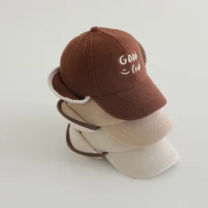 Detail view of stacked winter ear-protection baby baseball hats in brown and beige fleece