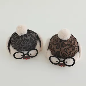 Detail of leopard print baby winter hat with plush pompom and novelty glasses decoration