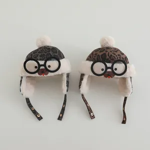 Detail view of leopard print baby trapper hat with fluffy pom-poms and decorative glasses