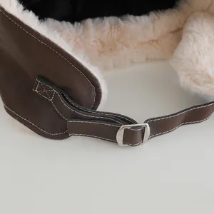 Detail of winter trapper hat showing brown faux leather texture and warm fleece lining