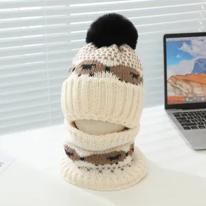 Détail d'un ensemble bonnet et écharpe en tricot avec motif ondulé et grand pompon en fourrure