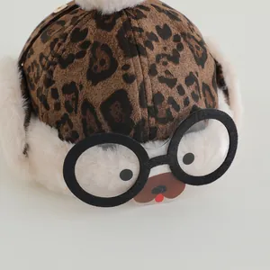 Close-up of leopard print winter hat with fuzzy pom-pom and cute decorative glasses detail