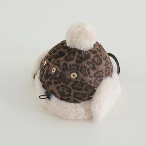 Detailed view of leopard print baby winter hat with plush faux fur trim and fluffy pom-pom