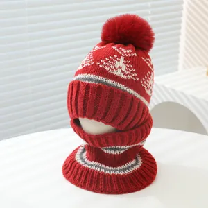 Detail of red winter knit hat and scarf set featuring snowflake patterns and faux fur pom