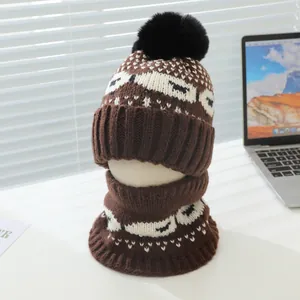 Détail d'un ensemble bonnet et écharpe en tricot marron pour enfant avec pompon noir