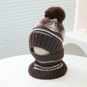 Detail of winter knit hat and neck gaiter set with snowflake patterns and brown fur pom-pom