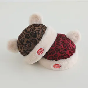 Detail of plush leopard print baby hats with white faux fur pom-poms and warm lining