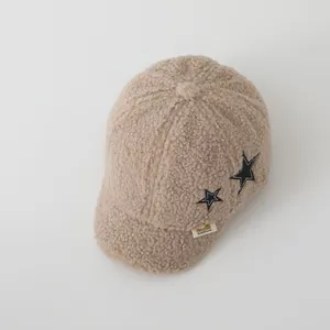 Dettaglio del cappellino neonato in pile beige con texture morbida e patch stelle