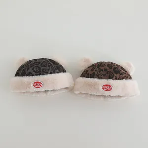 Detail of baby leopard print winter hats with fuzzy pom-poms and warm fleece lining