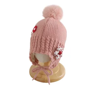 Bonnet en tricot rose pour bébé avec pompon en peluche et détails floraux délicats
