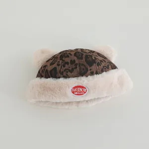 Detailed view of winter baby leopard hat featuring plush bear ears and red embroidered label