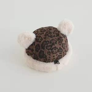 Detail of baby leopard print hat with white plush pom-poms and adjustable drawstring
