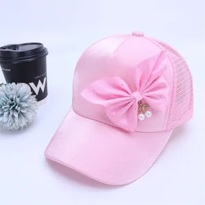 Detalle de gorra rosa de malla con gran lazo de seda y colgante de cereza perlada