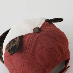 Détail de casquette bébé avec texture matelassée, oreilles léopard et fausse laine