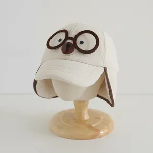 Detail van de beige fleece babymuts met schattig berengezicht en decoratieve bril-look
