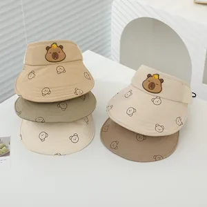 Dettaglio di visiere parasole per bambini con toppe capibara in tonalità terra