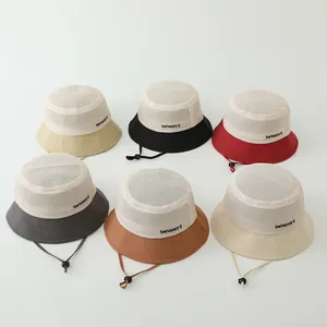 Détail de chapeaux de soleil en mesh colorés avec broderie 'behappy' et cordons réglables