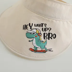 Detailaufnahme beiger Kinder-Sonnenhut mit niedlichem grünem Dinosaurier-Skater-Motiv