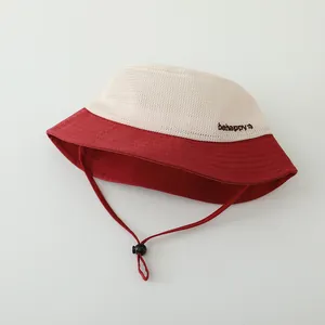 Détail du chapeau de soleil en maille rouge et beige avec broderie et cordon réglable