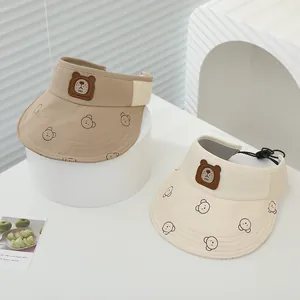 Dettaglio di visiere parasole per bambini beige con toppe a orsetto e cinturino