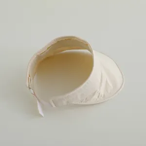 Detail of cream-colored sun visor with adjustable velcro strap and quick-dry fabric texture