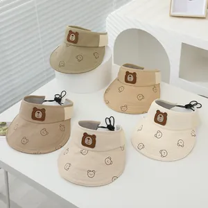 Dettaglio di cappellini parasole per bambini con stemmi a orsetto e cordini regolabili