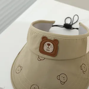 Dettaglio della visiera kaki per bambini con toppa a forma di orso e cordino elasticizzato