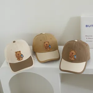 Close-up of kids baseball caps featuring a 3D cartoon bear patch in neutral earth tones