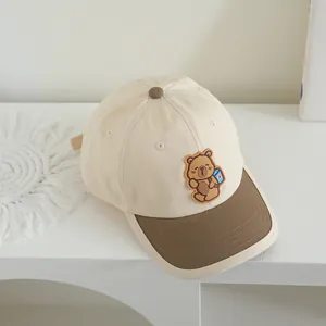 Detail of children's baseball cap featuring a cute cartoon bear patch and bicolor canvas