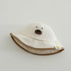Detail of cream baby sun hat with bear embroidery and contrast brown piping edge