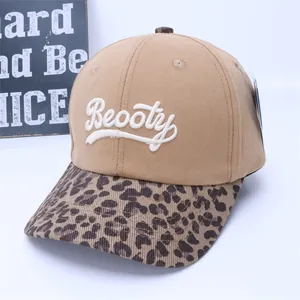 Detailed embroidery of white letters on a khaki cotton baseball cap with leopard brim