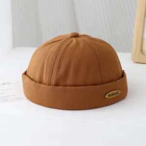Dettaglio del cappello Miki caramello con targhetta in metallo KUKUJI e tessuto