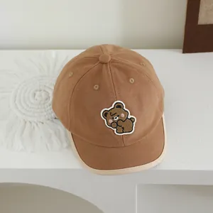 Detail van het beertje borduursel op de caramel katoenen kinderpet met klep