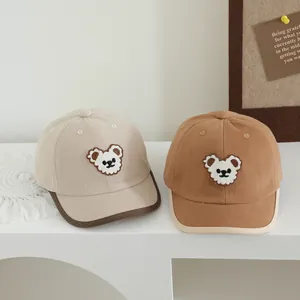 Detail van twee kinder baseballpetten in beige en bruin met 3D-beer borduurwerk