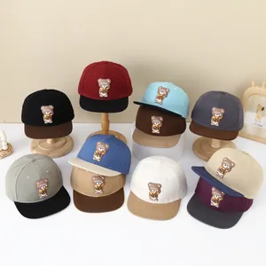 Close-up of children's flat brim baseball caps with 3D bear patch in multiple colors