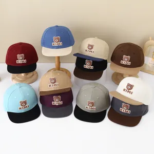 Detail view of colorful kids baseball caps featuring KIMI bear embroidery in various shades