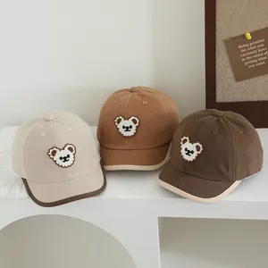 Detailopname van drie bruine kinderpetten met beer op witte geometrische blokken