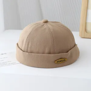 Dettaglio del berretto Miki kaki con logo metallico KUKUJI dorato e trama in twill di cotone
