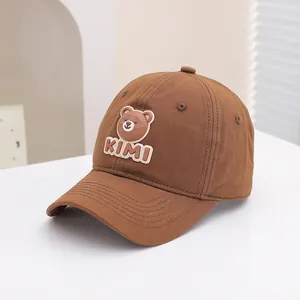 Detail of a dark brown kids baseball cap with a silicone 3D cartoon bear patch and KIMI text