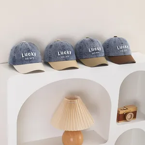 Detail of four denim baseball caps with Lucky embroidery in white, khaki, green, and brown