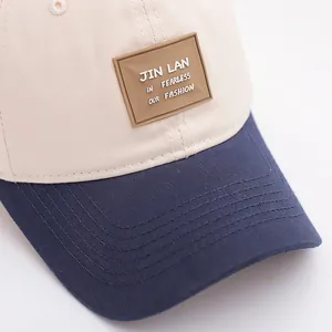 Detailopname van de stiksels op de beige en blauwe katoenen baseballpet voor kids met rubberen patch