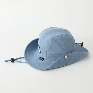 Detalle de sombrero de pescador denim azul para niños con botones metálicos y cordón ajustable