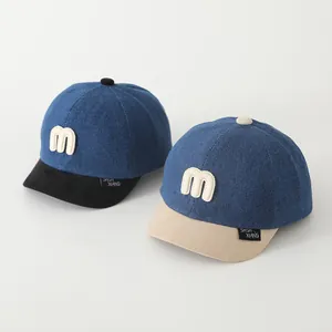Detailansicht der Kinder-Basecaps aus blauem Denim mit weichem Schirm und Stickerei