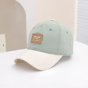 Detailopname van een lichtgroene en beige kinderhonkbalpet met bruine leren patch