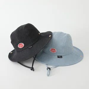 Detail view of denim bucket hats with red logo patch and adjustable windproof cords