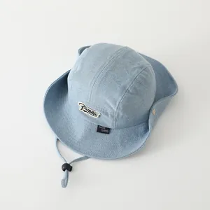 Detalle de gorro de sol en denim azul claro con textura, barboquejo y parche de logo
