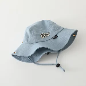 Detalle de gorro de pescador de mezclilla azul claro para niño con parche y cordón ajustable
