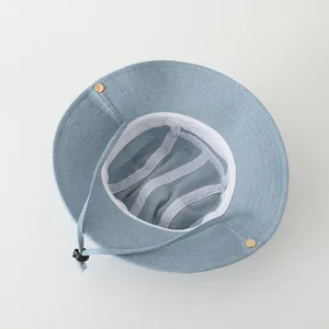 Detail view of denim bucket hat interior with adjustable drawstring and gold buttons