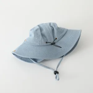 Detail of light blue denim bucket hat with adjustable black drawstring and windproof cord