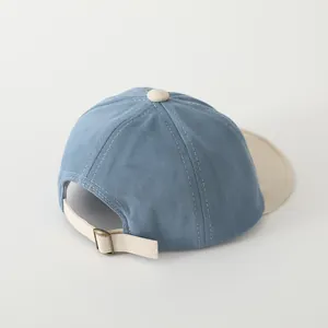 Dettaglio del cappellino da neonato in cotone blu con fibbia di regolazione in metallo beige
